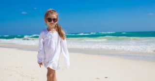 Adorable little girl relaxing and have fun at tropical white beach