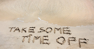 TAKE SOME TIME OFF written on sand on a beautiful beach blue waves in background